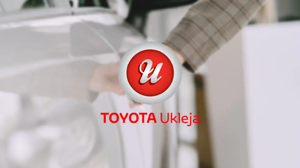 Logo Toyota Ukleja na tle otwieranych drzwi białego samochodu