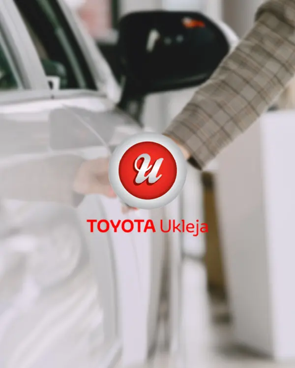 Logo Toyota Ukleja na tle otwieranych drzwi białego samochodu