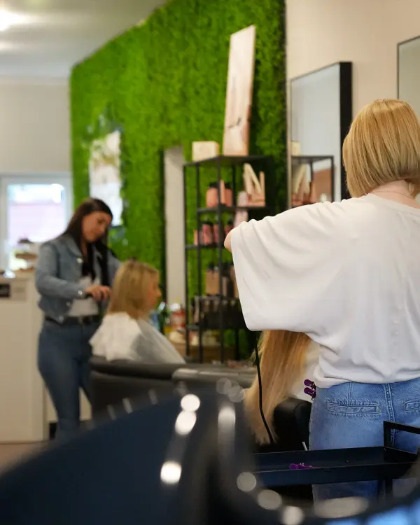 Fryzjerki przy pracy we wnętrzu salonu Perfect Color ze ścianą z mchu